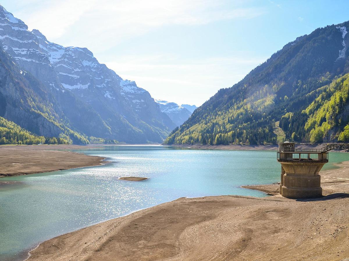 A reservoir at low water levels, with mountains in the background